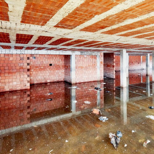 The basement of a building under construction is filled with dirty flood water
